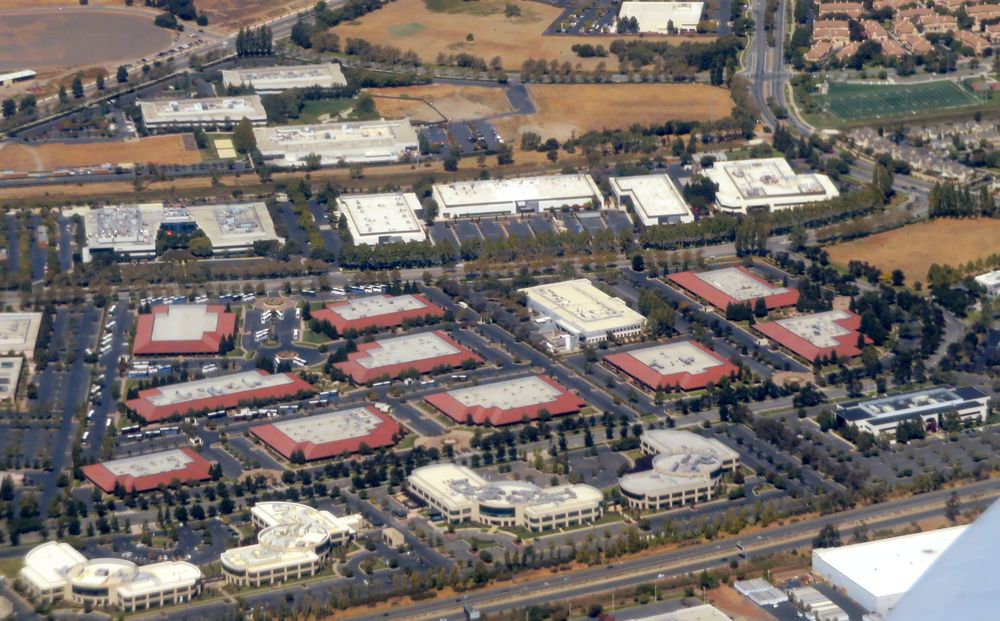 Flat-roofed office buildings in a business park, seen from the air.