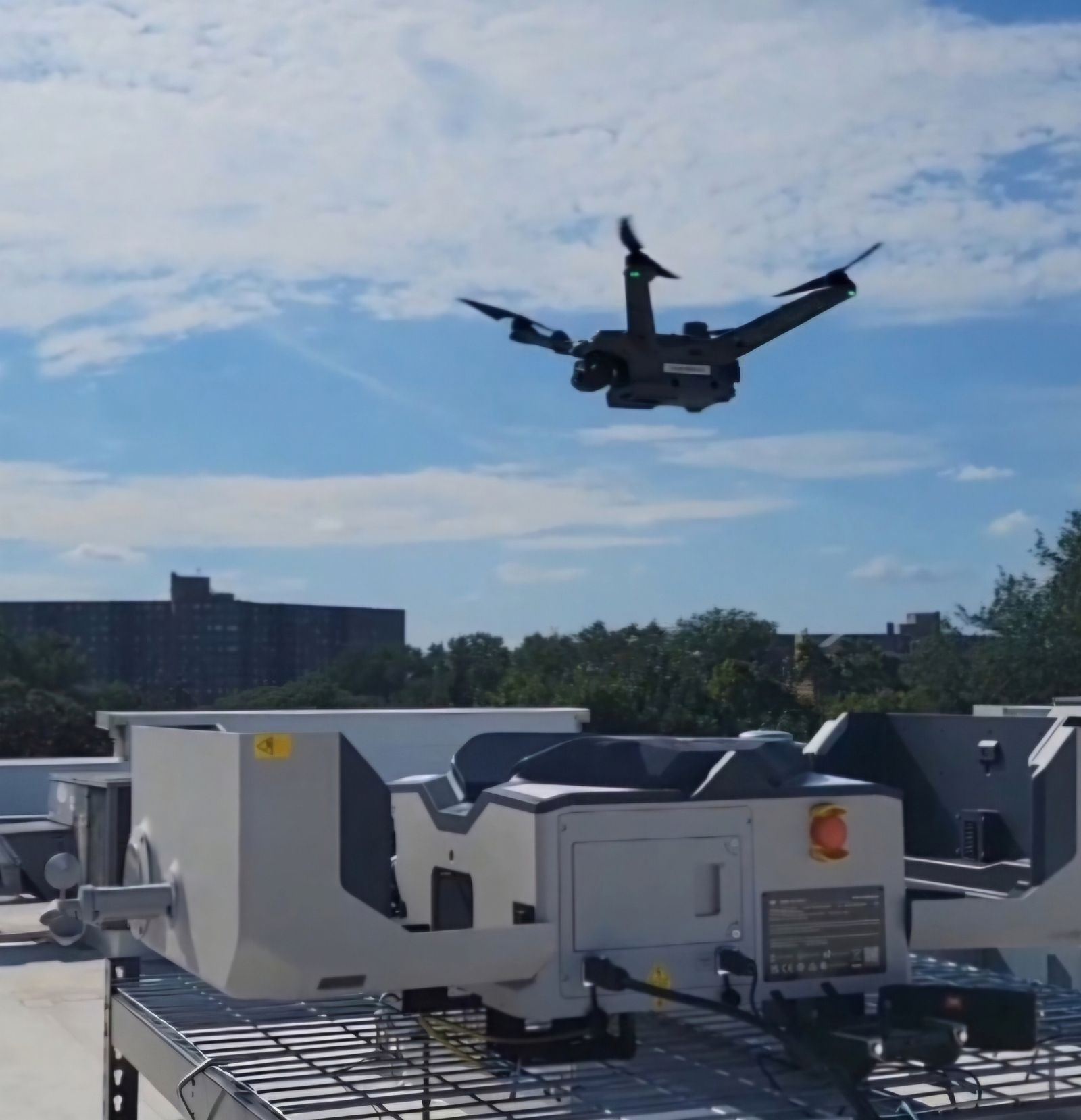 A drone flying low over the plant equipment on a flat commercial rooftop.